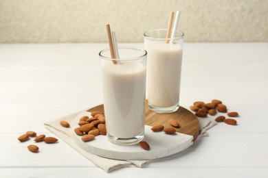 Glasses of almond milk and almonds on white wooden table