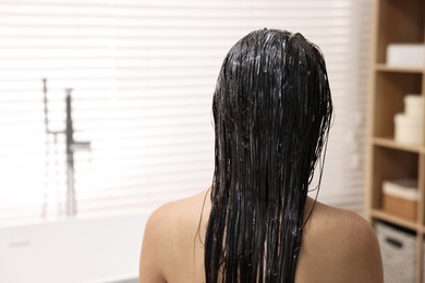 Photo of Woman with applied hair mask in bathroom, back view. Space for text