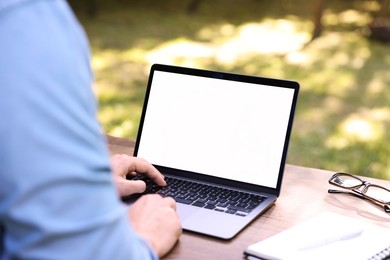 Photo of Freelancer working with laptop at table outdoors, closeup. Remote job