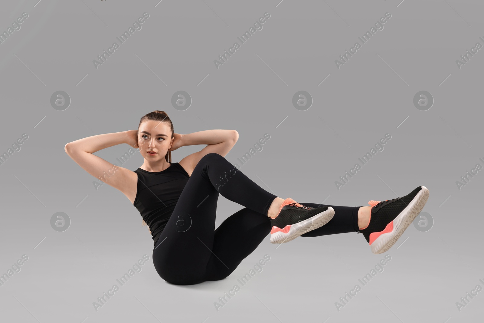 Photo of Young woman doing aerobic exercise on light background