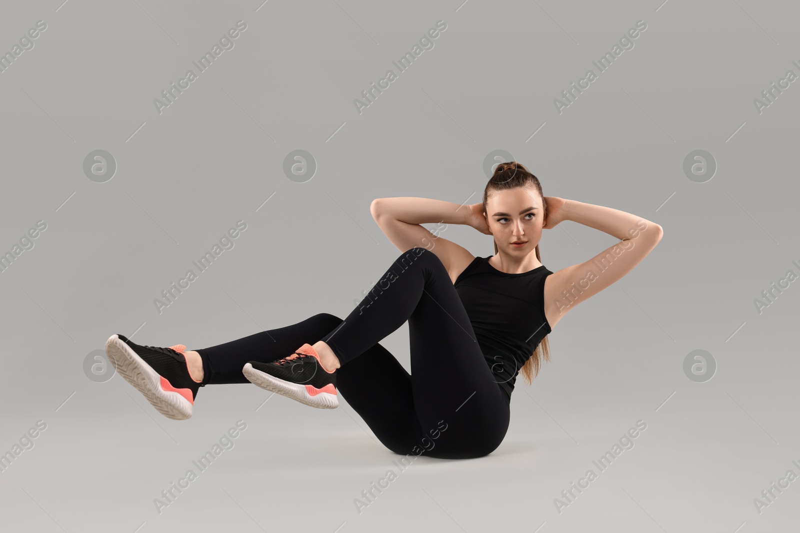 Photo of Young woman doing aerobic exercise on light background