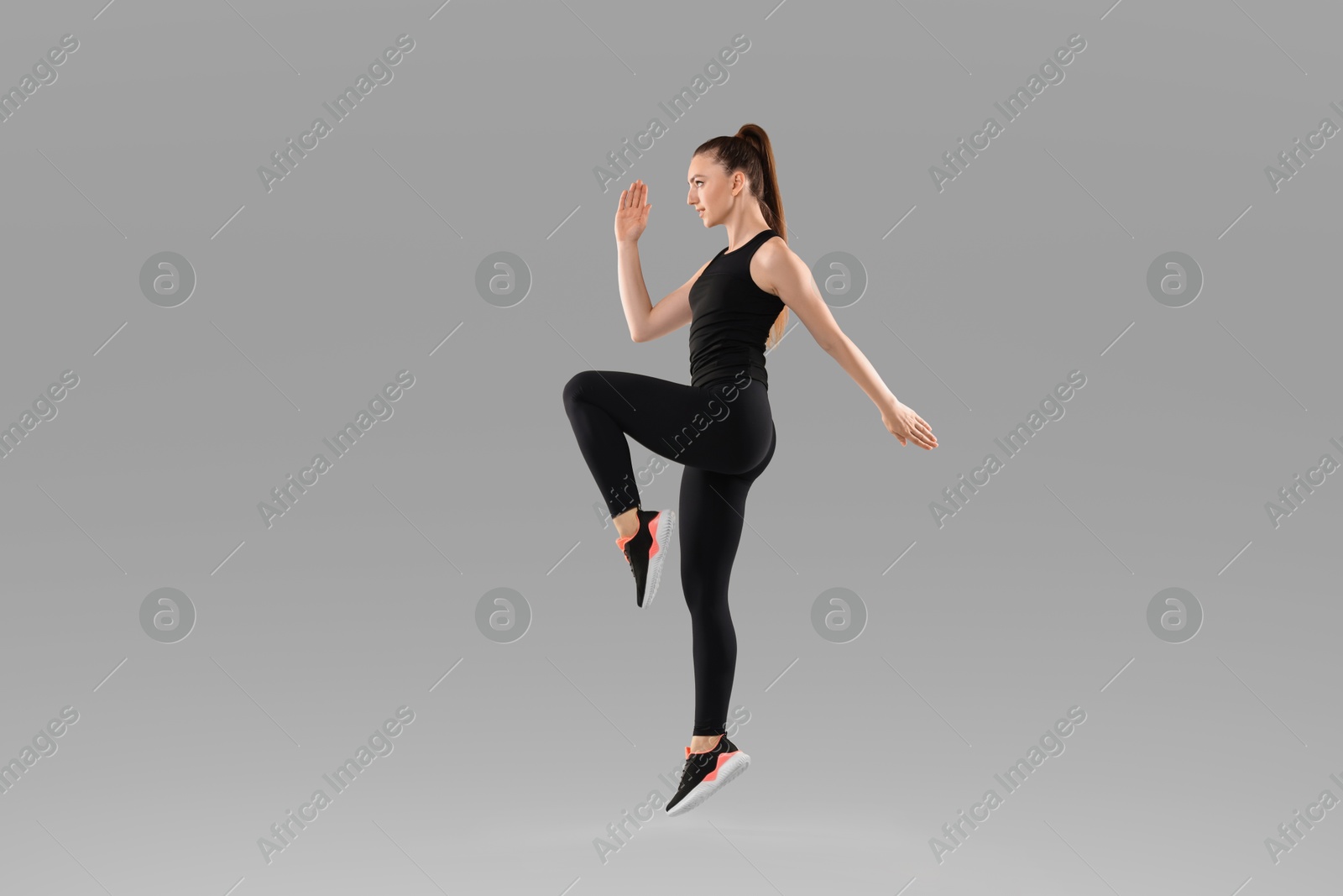 Photo of Young woman doing aerobic exercise on light background