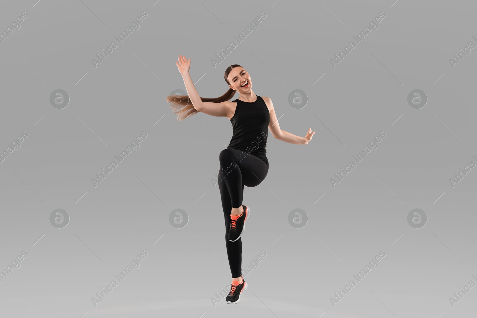 Photo of Young woman doing aerobic exercise on light background