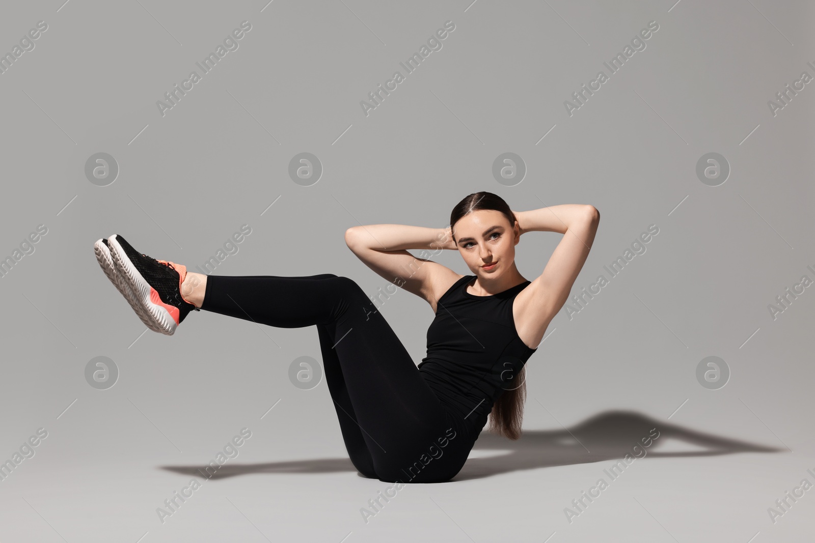 Photo of Young woman doing aerobic exercise on light grey background