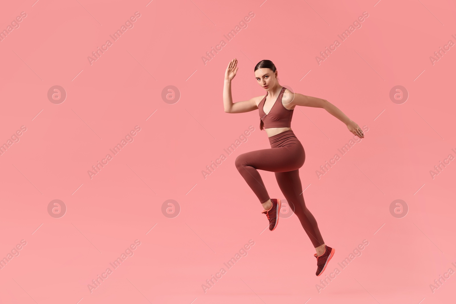 Photo of Young woman doing aerobic exercise on pink background. Space for text