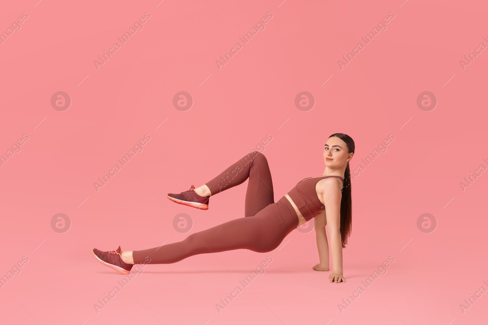 Photo of Young woman doing aerobic exercise on pink background