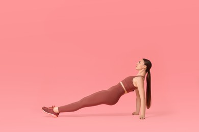 Photo of Young woman doing aerobic exercise on pink background