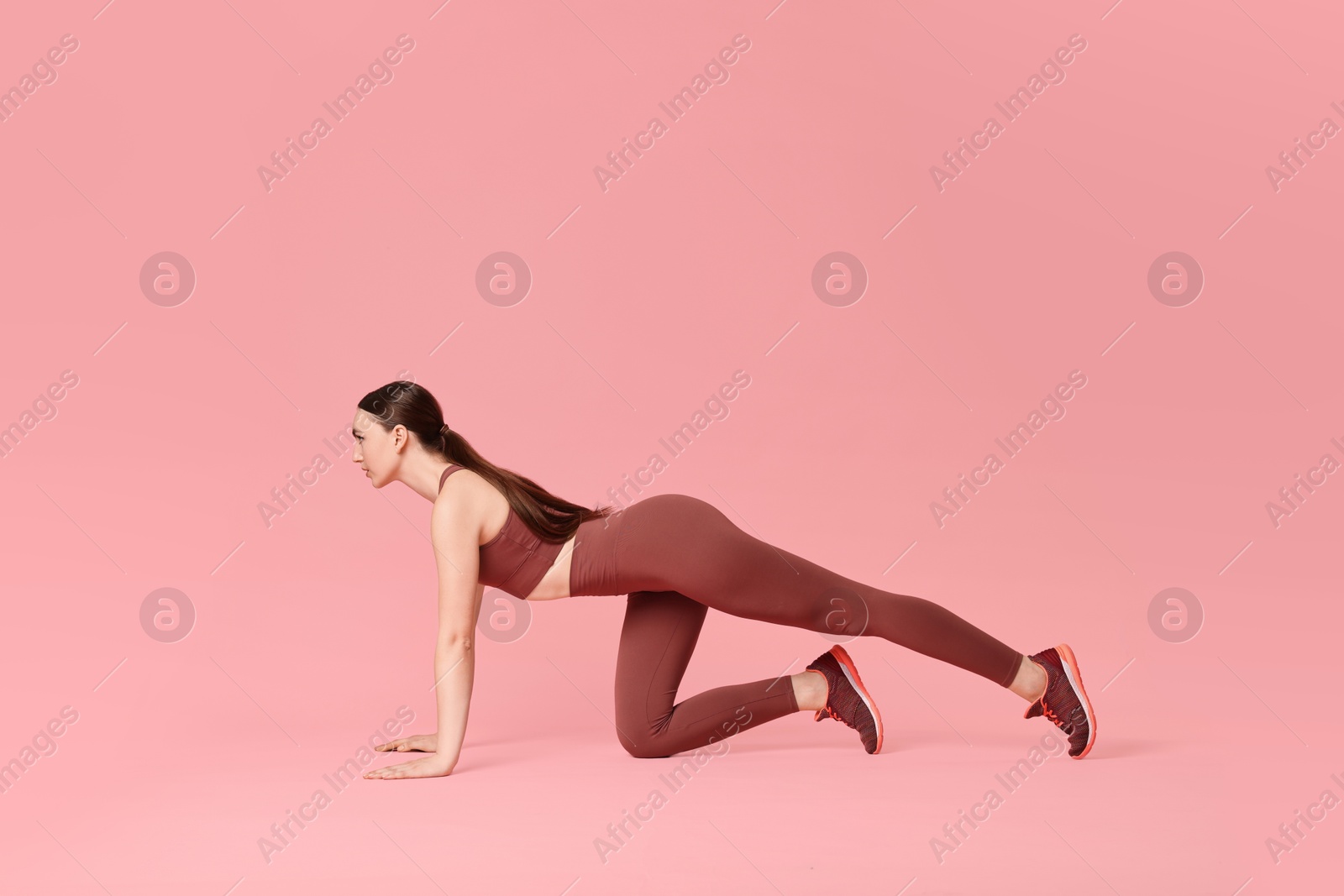 Photo of Young woman doing aerobic exercise on pink background