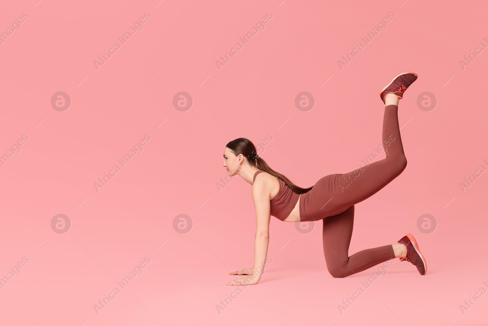 Photo of Young woman doing aerobic exercise on pink background