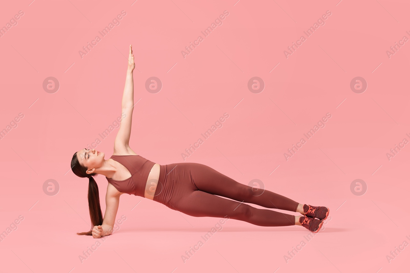 Photo of Young woman doing aerobic exercise on pink background