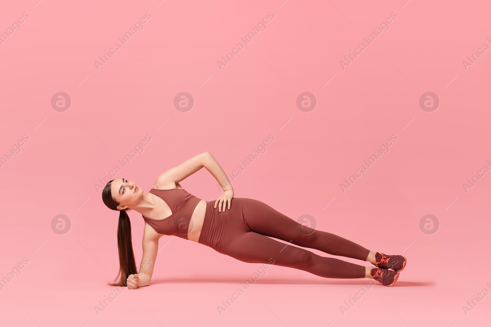 Photo of Young woman doing aerobic exercise on pink background