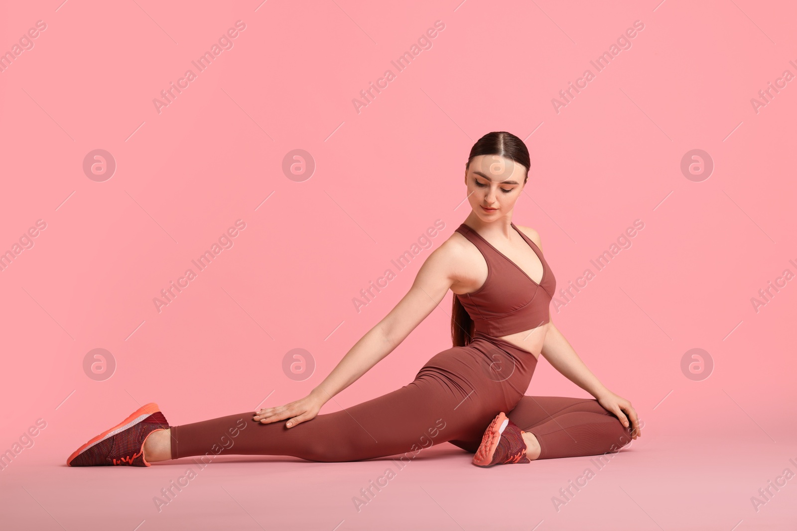 Photo of Aerobics. Young woman doing stretching exercise on pink background