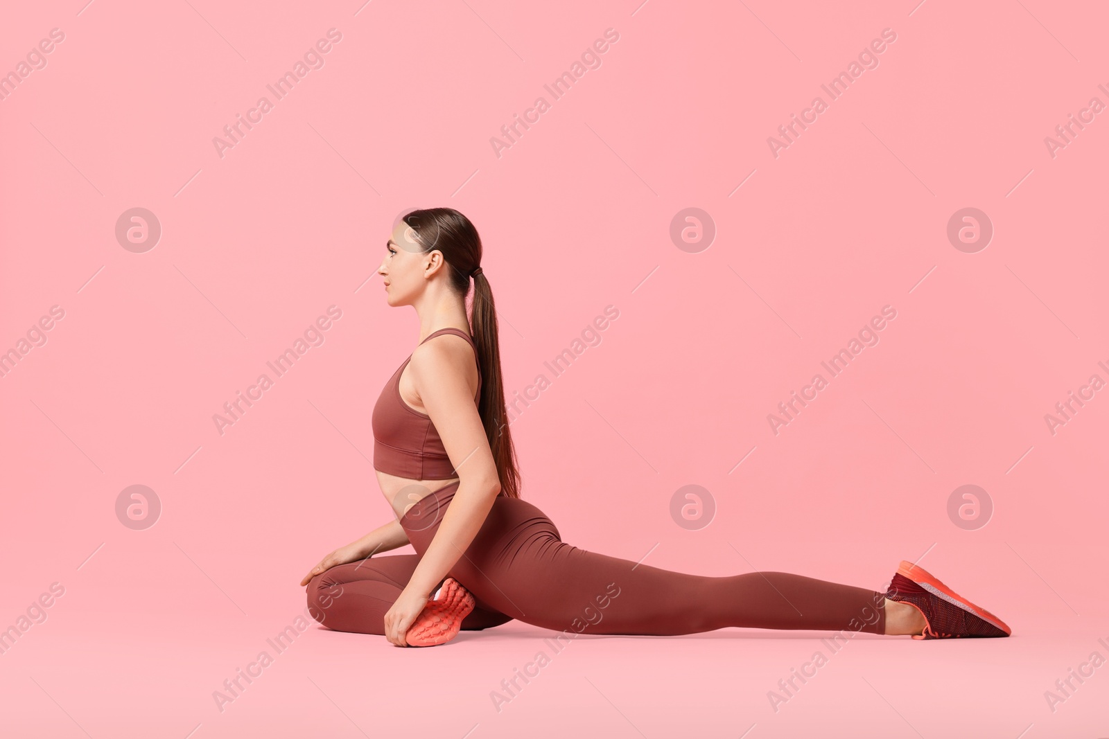 Photo of Aerobics. Young woman doing stretching exercise on pink background