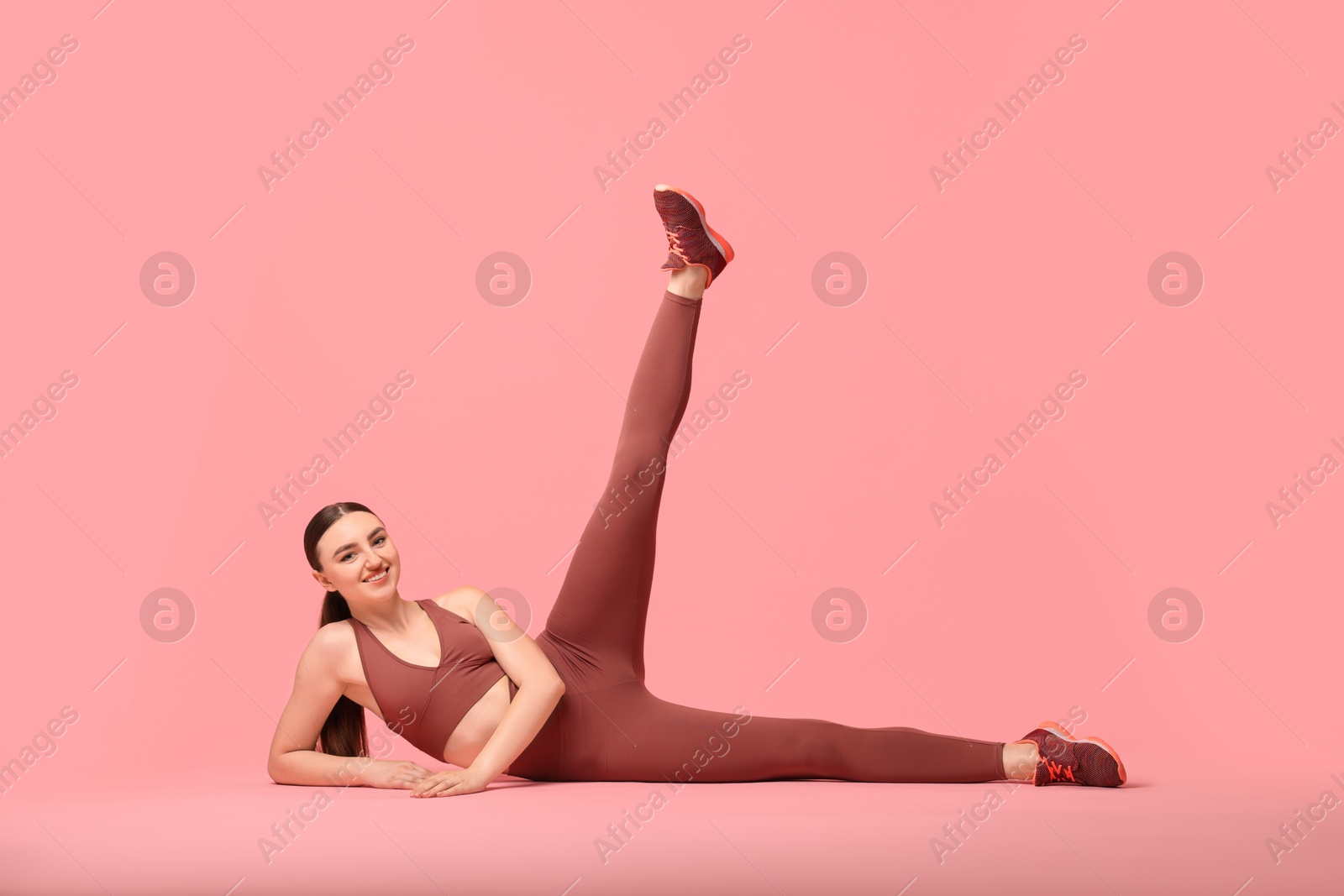 Photo of Aerobics. Young woman doing stretching exercise on pink background