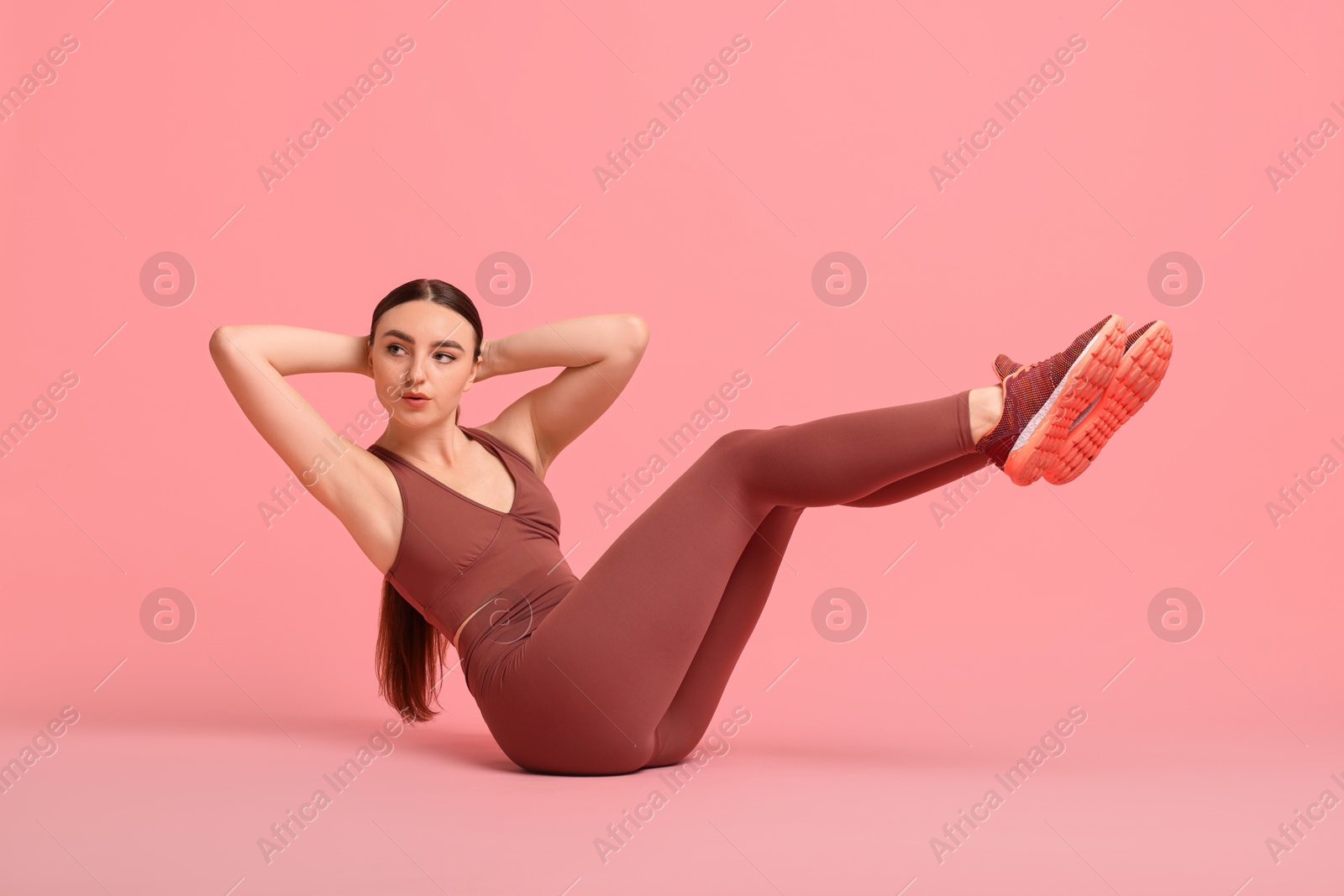 Photo of Young woman doing aerobic exercise on pink background