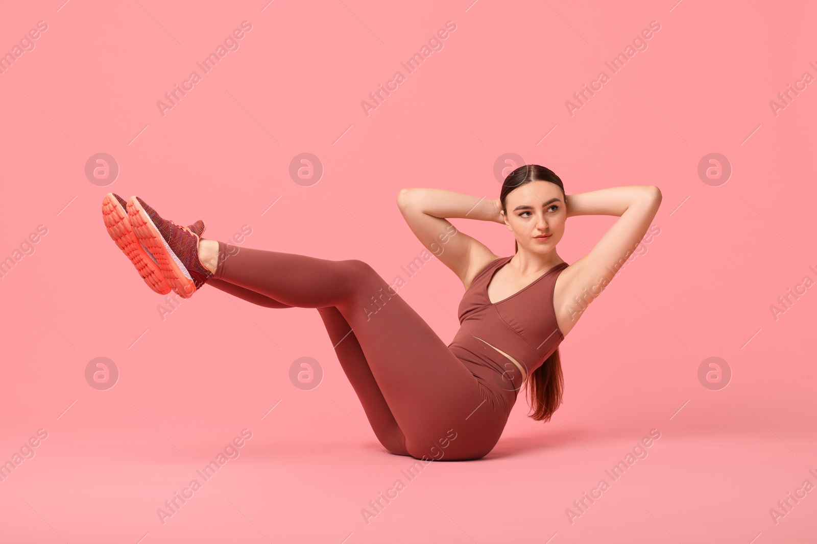 Photo of Young woman doing aerobic exercise on pink background