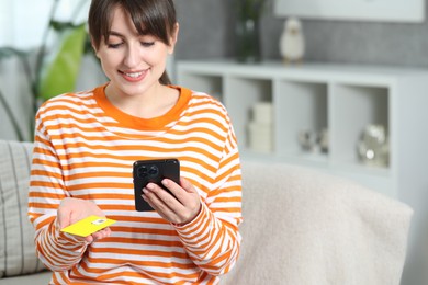 Photo of Woman holding SIM card and smartphone on sofa indoors, space for text