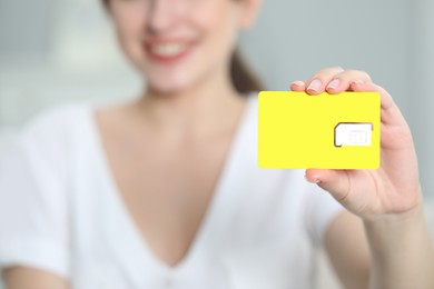 Photo of Woman holding SIM card at home, closeup