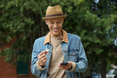 Photo of Happy man with SIM cards and smartphone outdoors