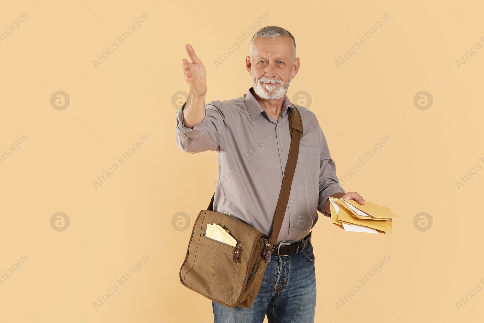 Photo of Happy postman with brown bag delivering letters on beige background