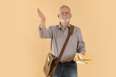 Photo of Happy postman with brown bag delivering letters on beige background