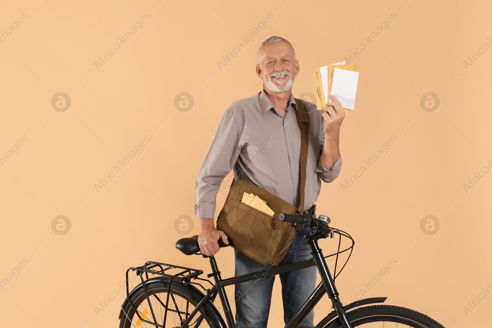 Photo of Happy postman with bicycle delivering letters on beige background