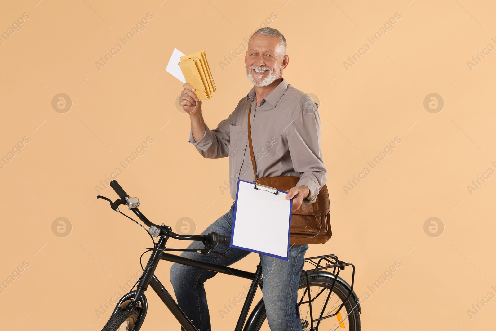 Photo of Happy postman with bicycle delivering letters on beige background