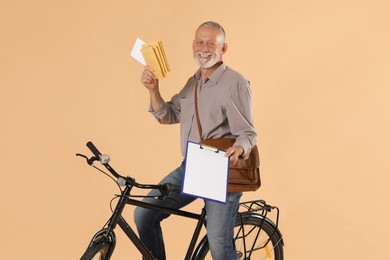 Photo of Happy postman with bicycle delivering letters on beige background