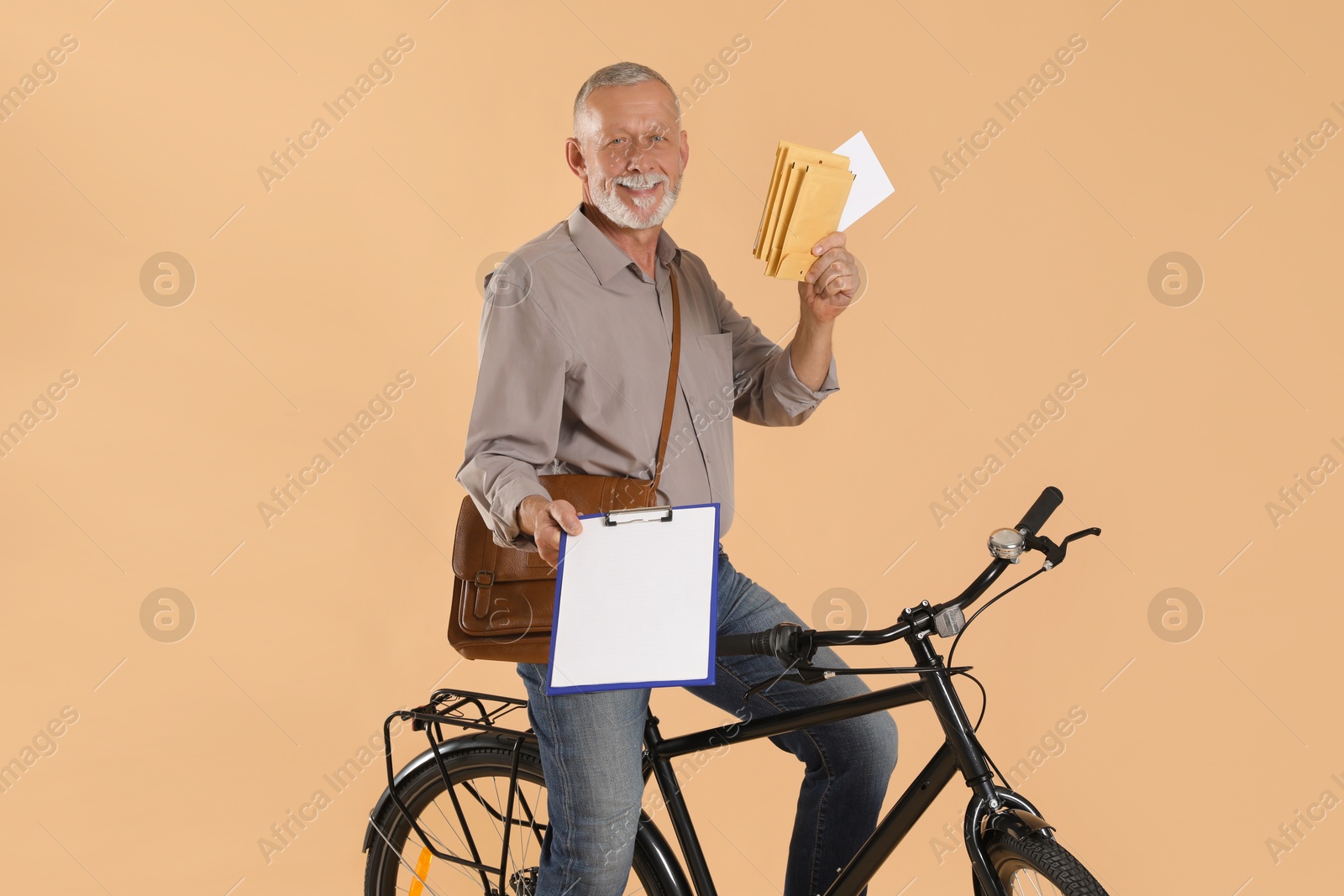 Photo of Happy postman with bicycle delivering letters on beige background