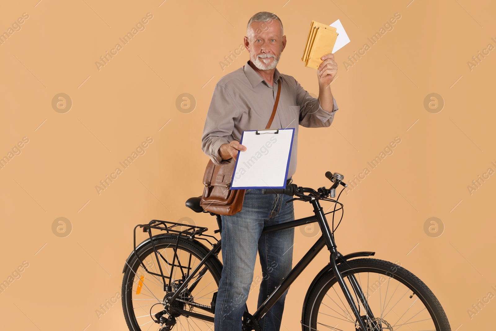 Photo of Happy postman with bicycle delivering letters on beige background