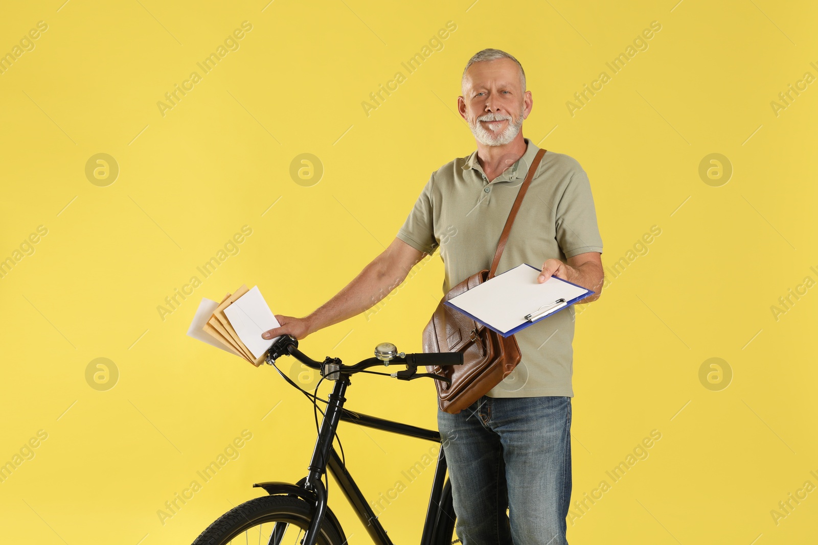 Photo of Postman with bicycle delivering letters on yellow background