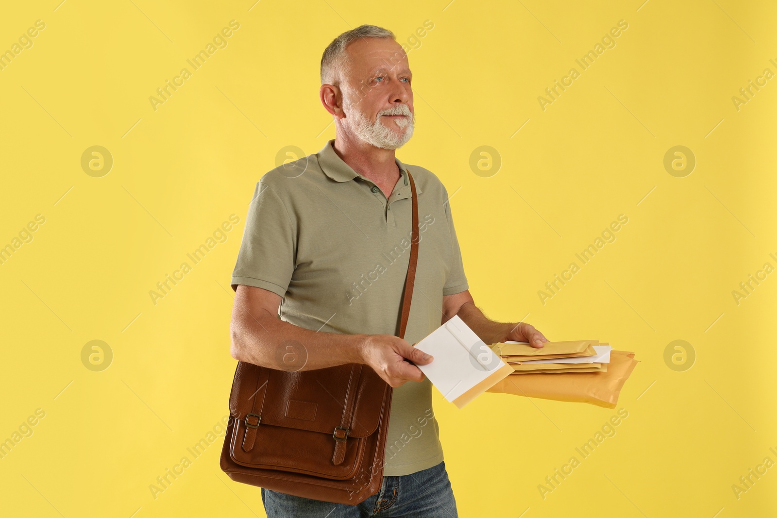 Photo of Postman with brown bag delivering letters on yellow background