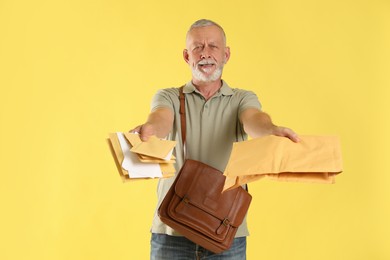 Photo of Happy postman with brown bag delivering letters on yellow background