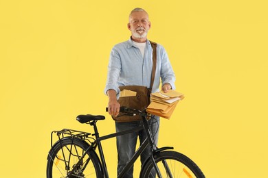 Photo of Postman with bicycle delivering letters on yellow background