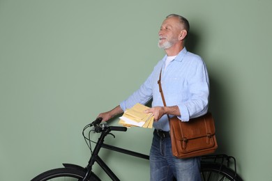 Photo of Postman with bicycle delivering letters on olive background