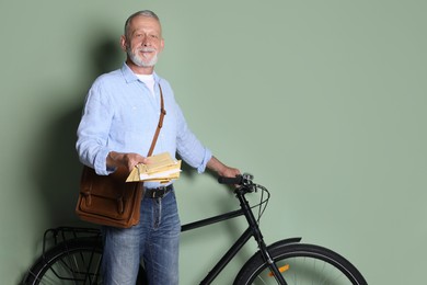 Photo of Postman with bicycle delivering letters on olive background. Space for text