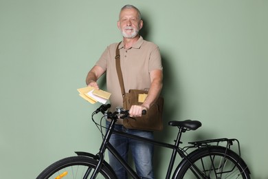 Photo of Postman with bicycle delivering letters on olive background