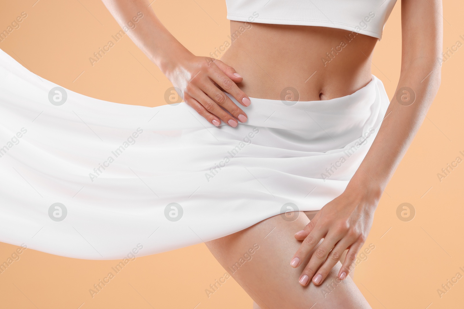 Photo of Diet and weight loss concept. Woman covering her slim body with silk fabric against beige background, closeup