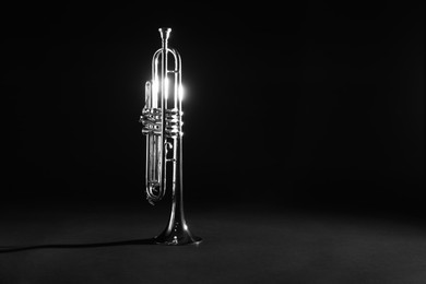 Photo of Shiny trumpet on dark background, space for text. Wind musical instrument