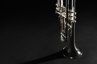 Photo of Closeup view of shiny trumpet on black background, space for text. Wind musical instrument