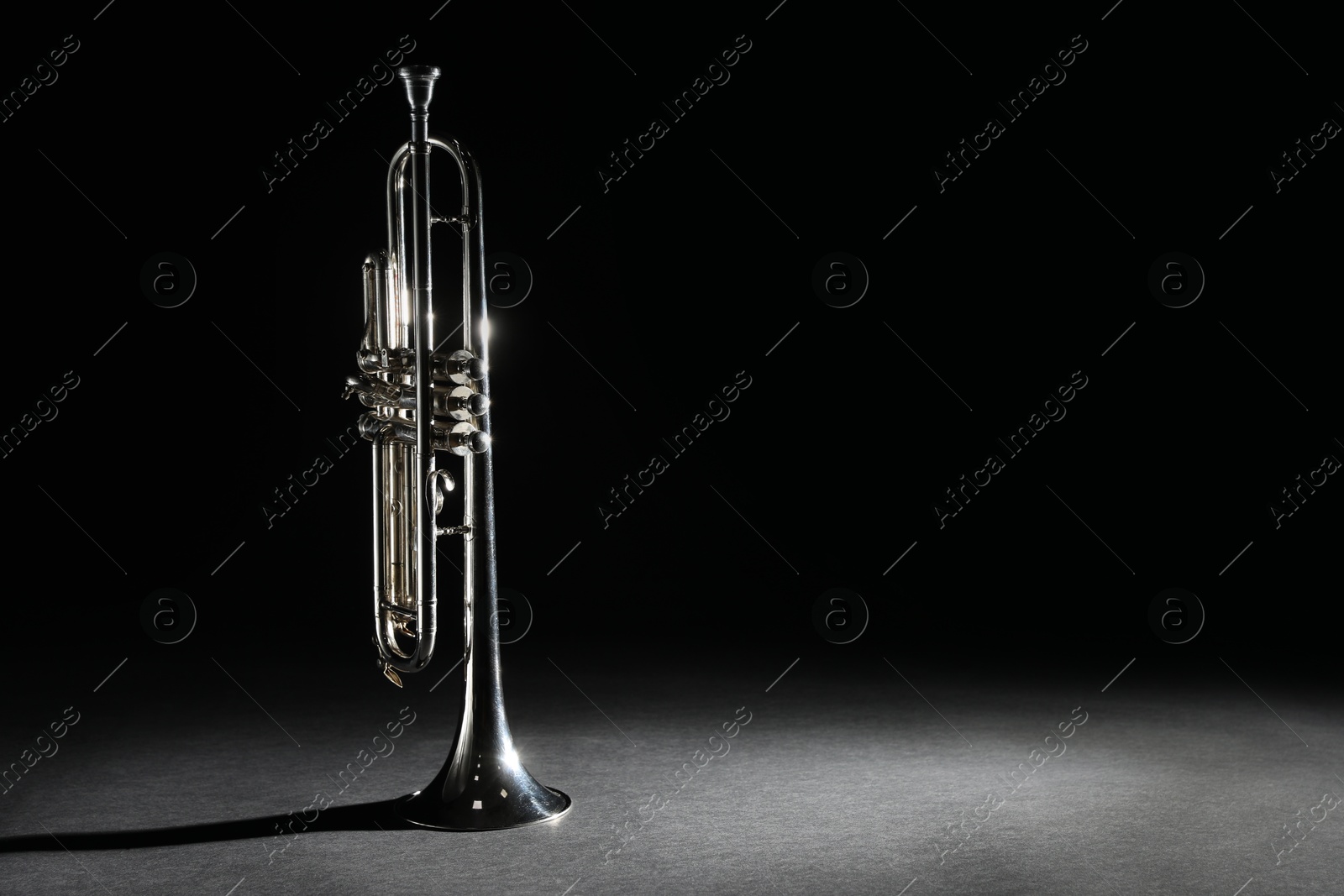 Photo of Shiny trumpet on black background, space for text. Wind musical instrument