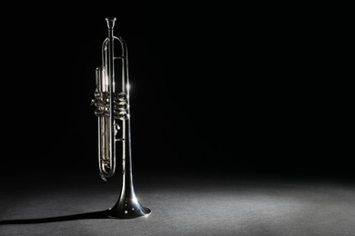 Shiny trumpet on black background, space for text. Wind musical instrument