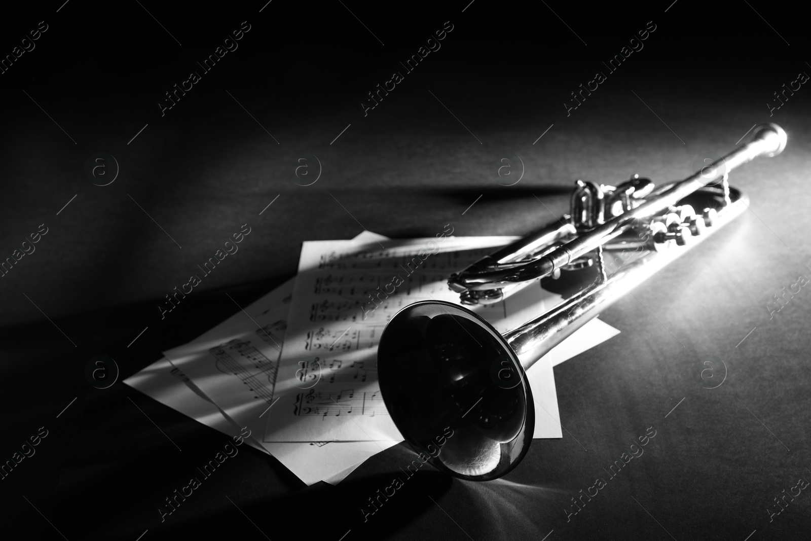 Photo of Shiny trumpet and music sheets on dark background. Wind musical instrument