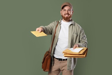 Photo of Happy young postman with brown bag delivering letters on olive background