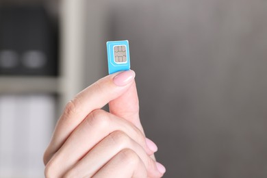 Photo of Woman holding SIM card indoors, closeup view