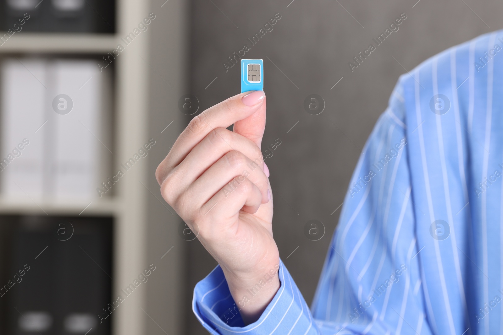 Photo of Woman holding SIM card indoors, closeup view