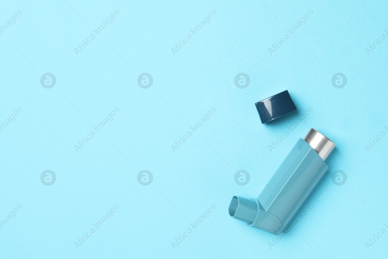 Photo of Asthma inhaler on light blue background, top view. Space for text