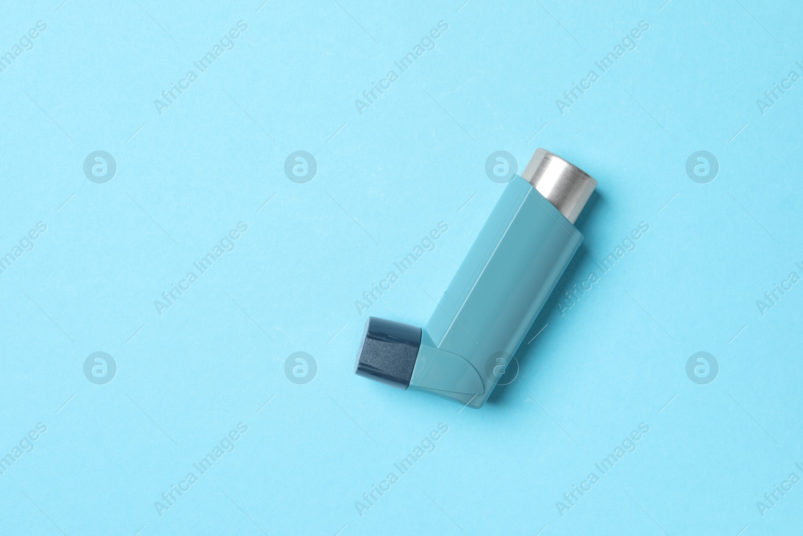 Photo of Asthma inhaler on light blue background, top view. Space for text