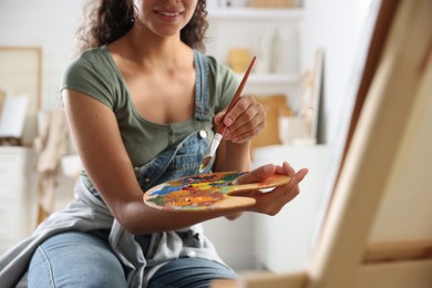 Smiling woman drawing picture with paint in studio, closeup