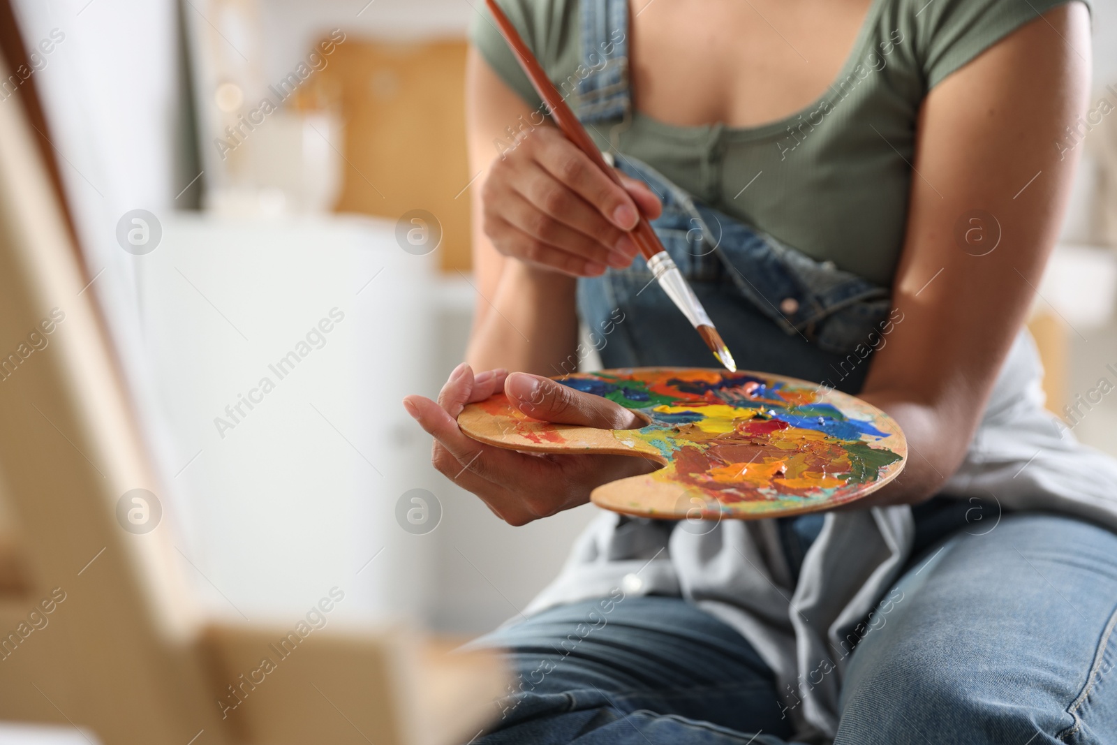 Photo of Woman drawing picture with paint in studio, closeup